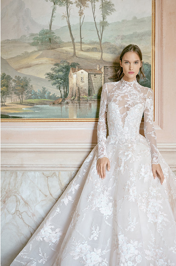 Woman wearing Monique Lhuillier Fall 2020 blush embroidered Wish ballgown with plunging sweetheart neckline and long-sleeve jacket
