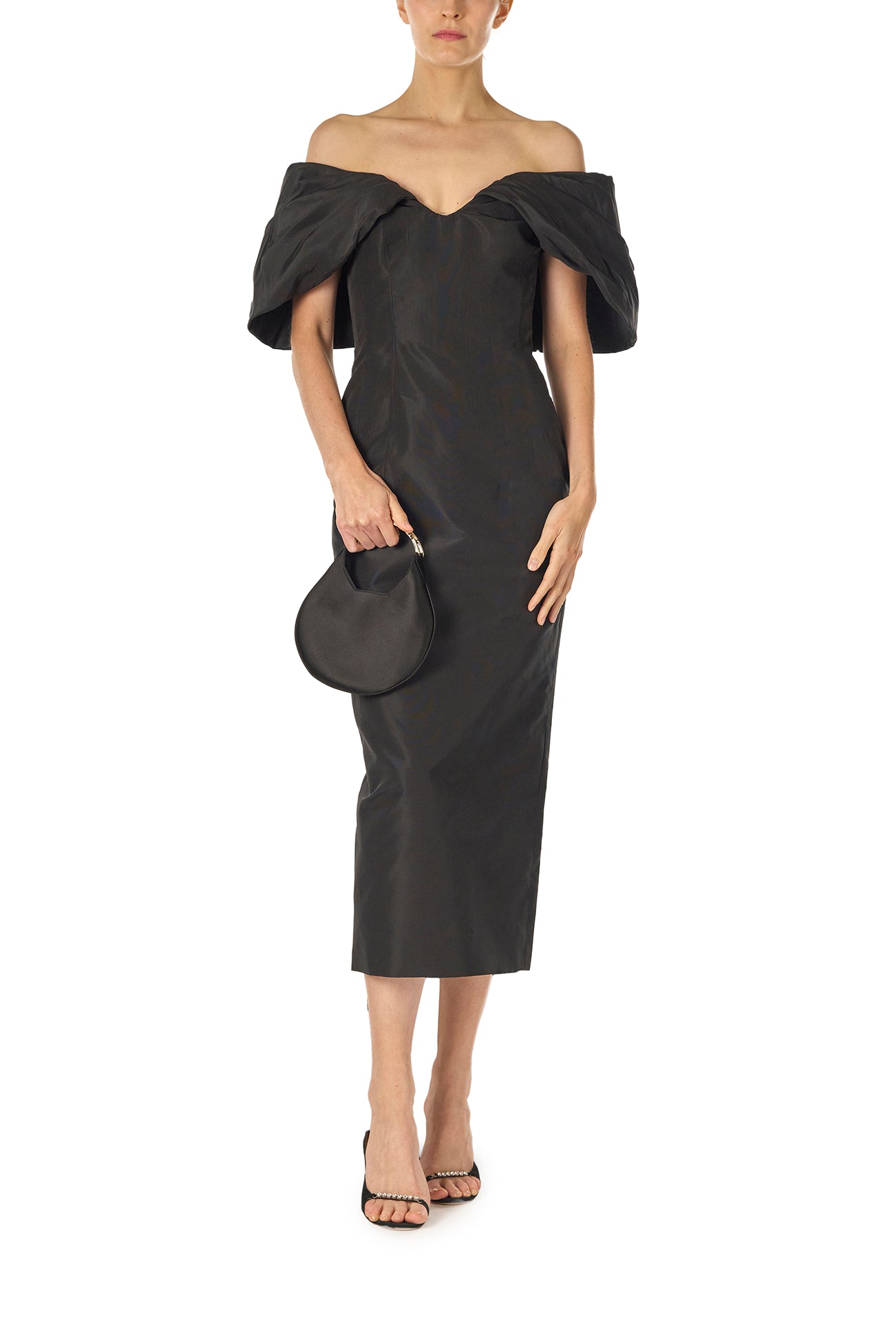 Monique Lhuillier Fall 2024 Off-the-shoulder tea length column dress with draped neckline and train in noir silk faille - front with Demi bag.