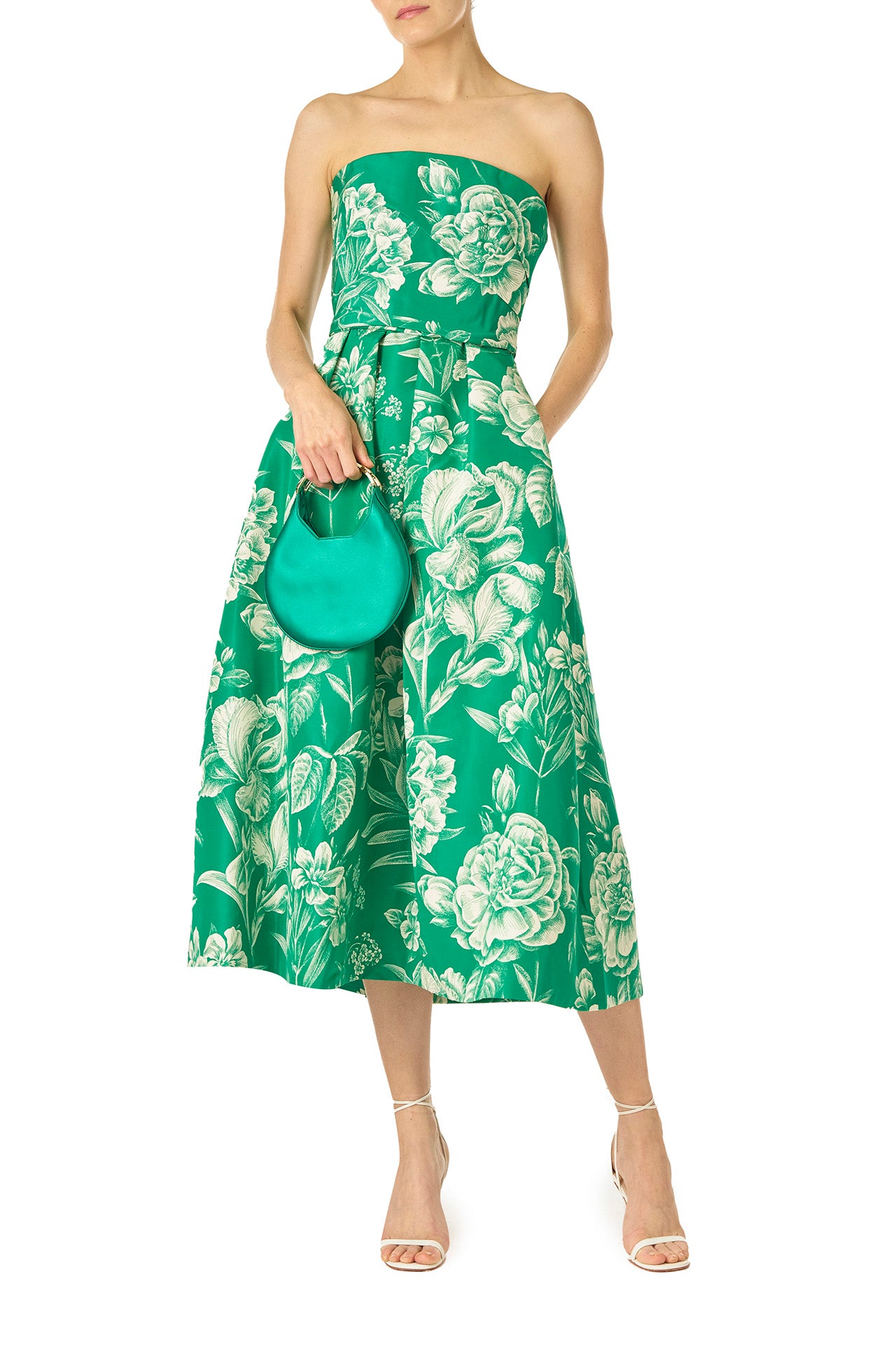 Monique Lhuillier Spring 2025 Strapless, tea-length dress with draped bodice and pockets in Grass/Silk White Floral Toile print - front with Demi bag in emerald satin.