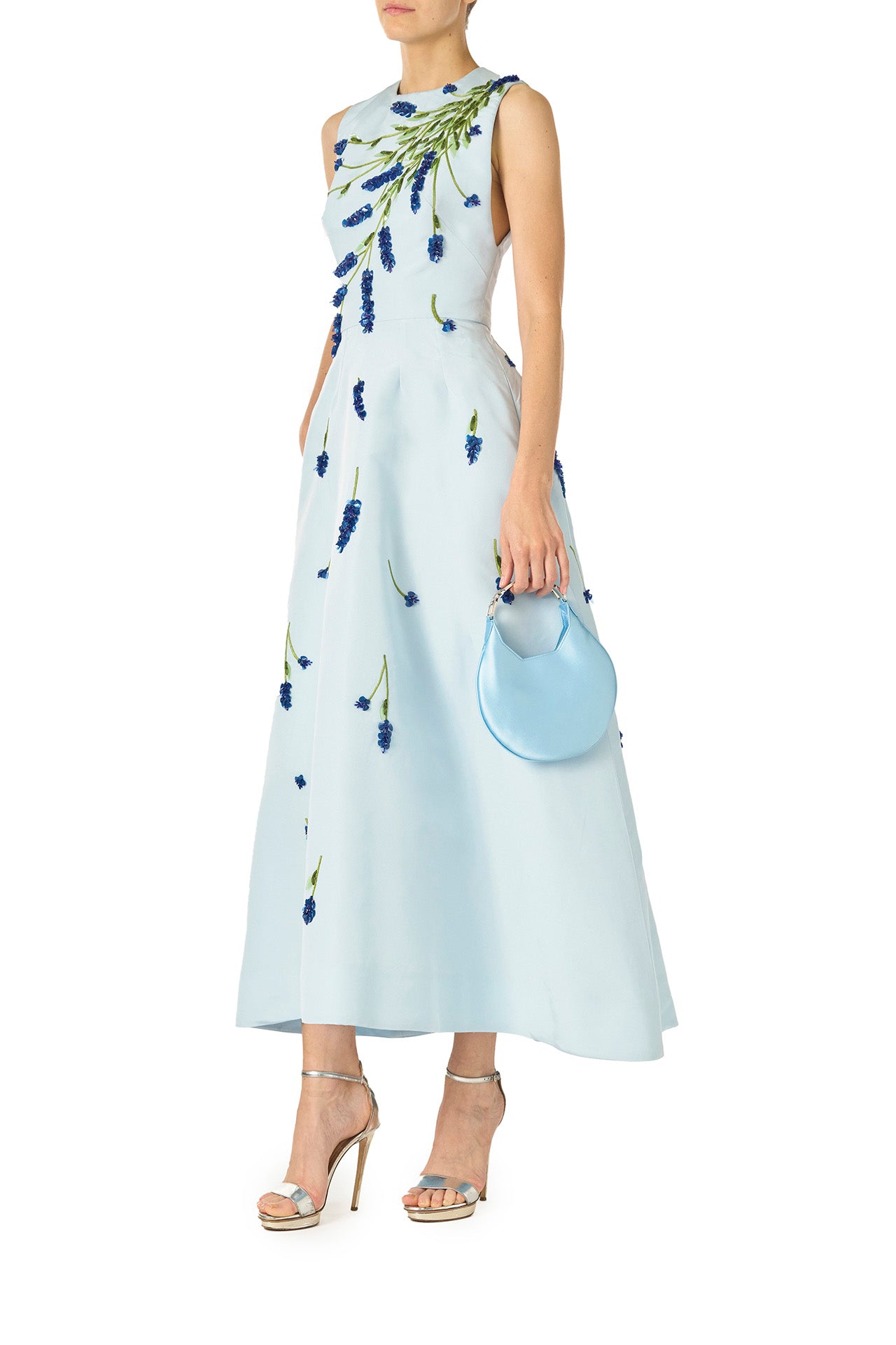 Monique Lhuillier Spring 2025 Sleeveless, tea-length dress with pockets in Powder Blue faille with Lavender-patterned embroidery - left side with Demi blue bag.