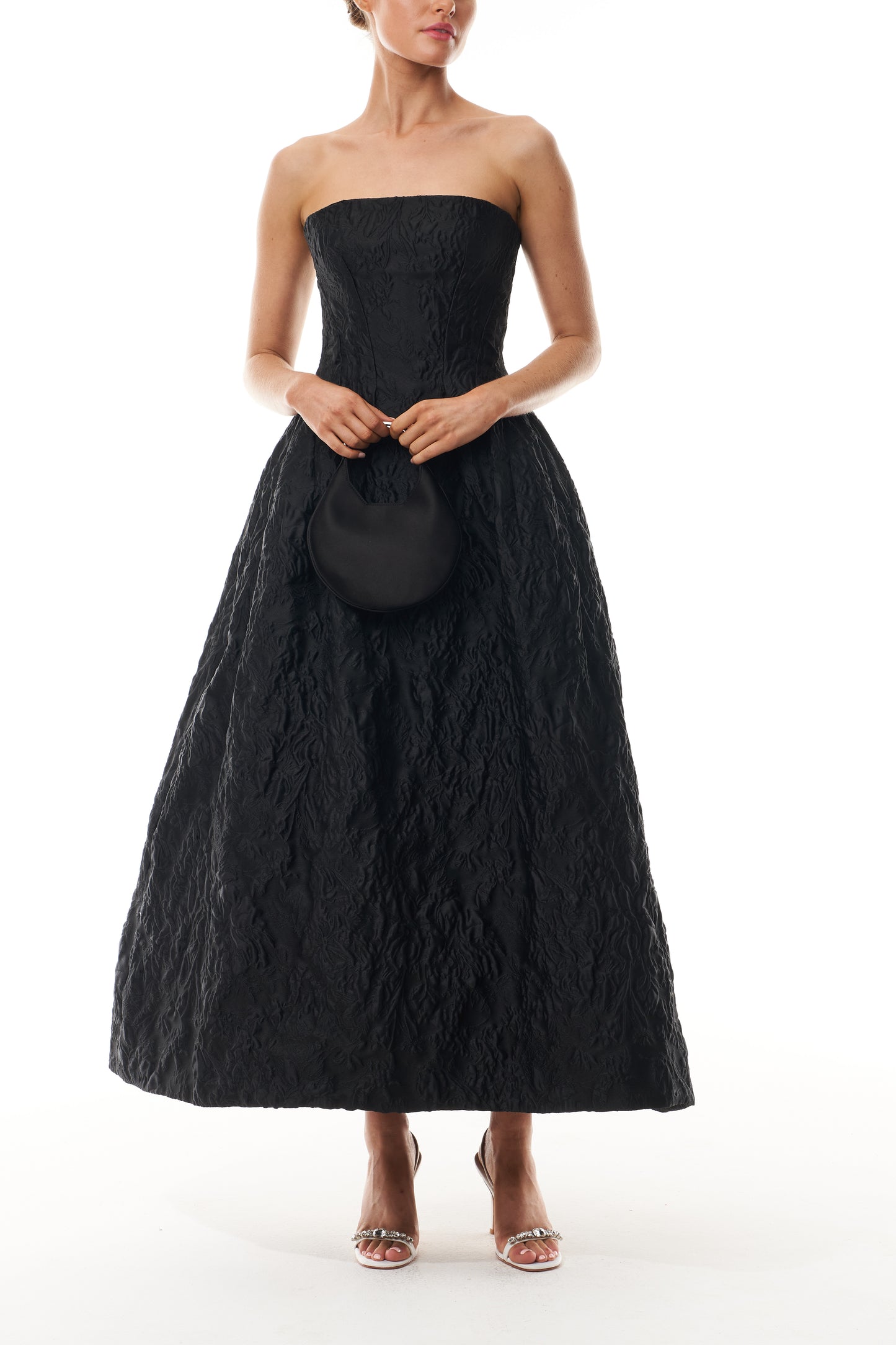 Monique Lhuillier Fall 2025 strapless midi-length dress with pockets in noir floral jacquard - front with Demi bag.