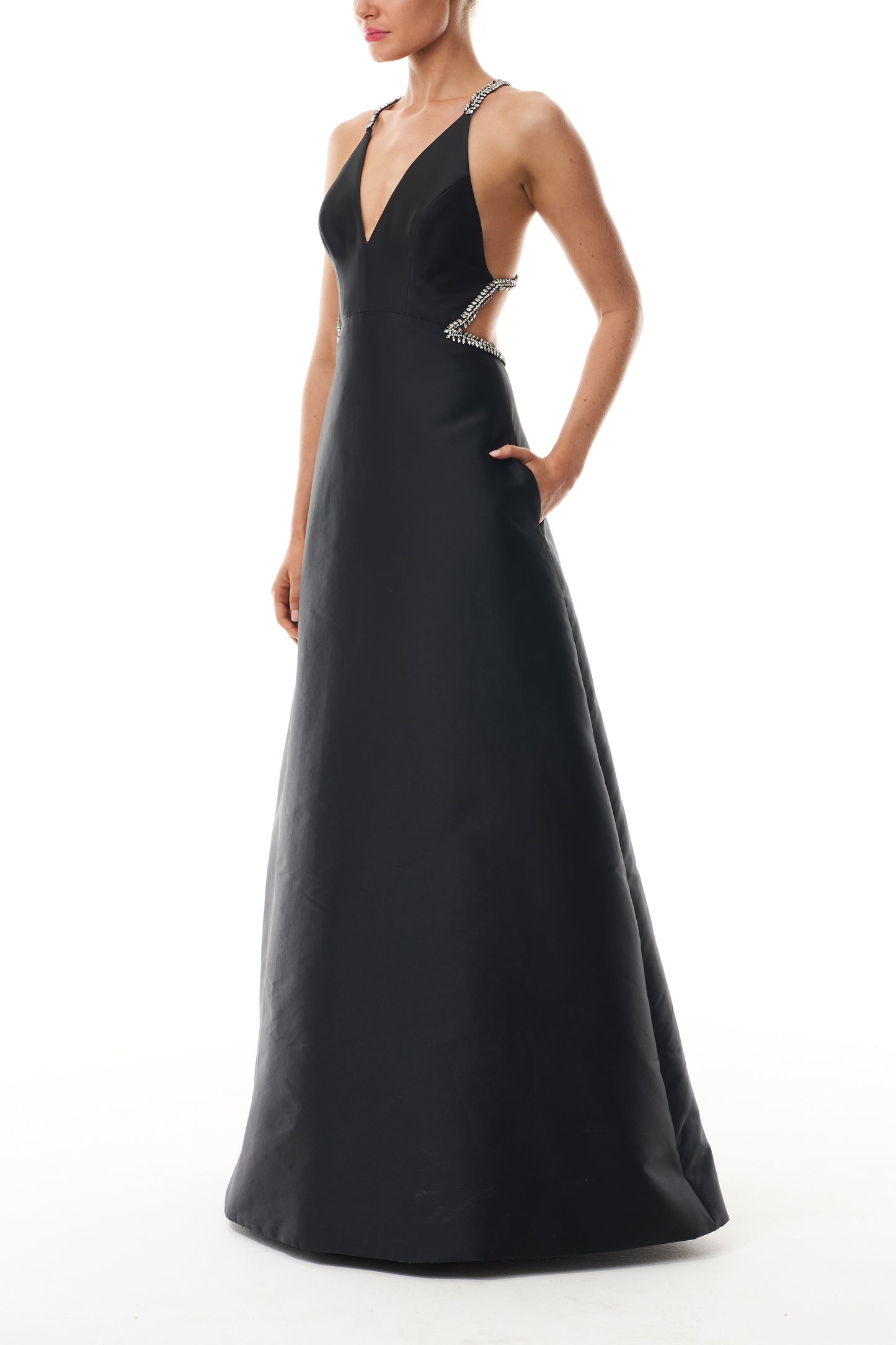 Monique Lhuillier Fall 2025 floor length ball gown with cut-out details and crystal embroidered piping in noir mikado - side.