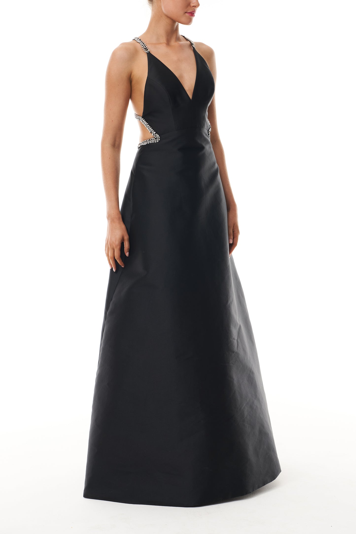 Monique Lhuillier Fall 2025 floor length ball gown with cut-out details and crystal embroidered piping in noir mikado - side.