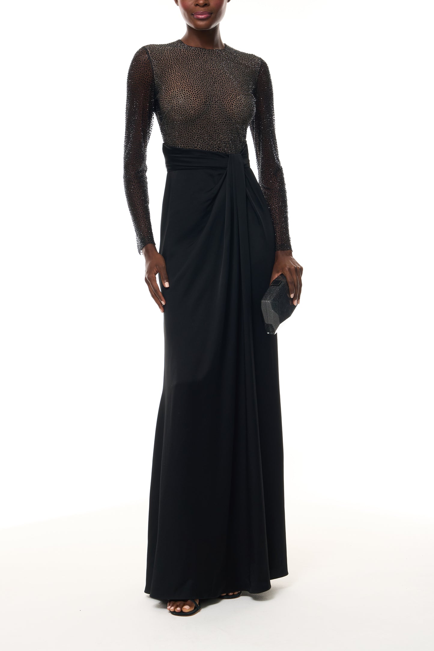 Monique Lhuillier Fall 2025 RTW Noir Long Sleeve Hotfix gown with embellished bodice and front slit - front with Noir Glitter Dasha Minaudiere.