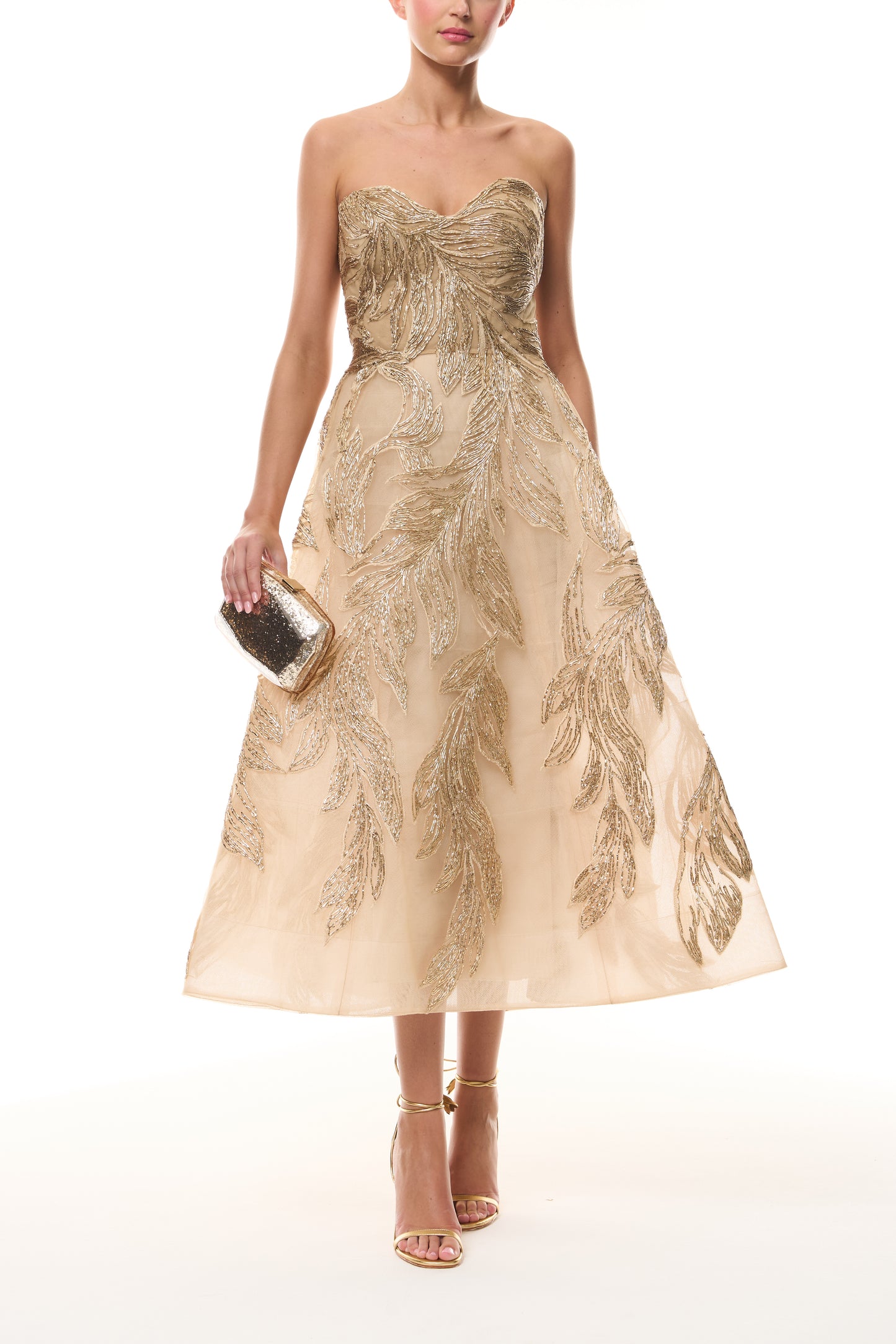 Monique Lhuillier Fall 2025 strapless dress with tea-length skirt and sweetheart neckline in gold feather embroidery - front with gold Dasha Minaudière.