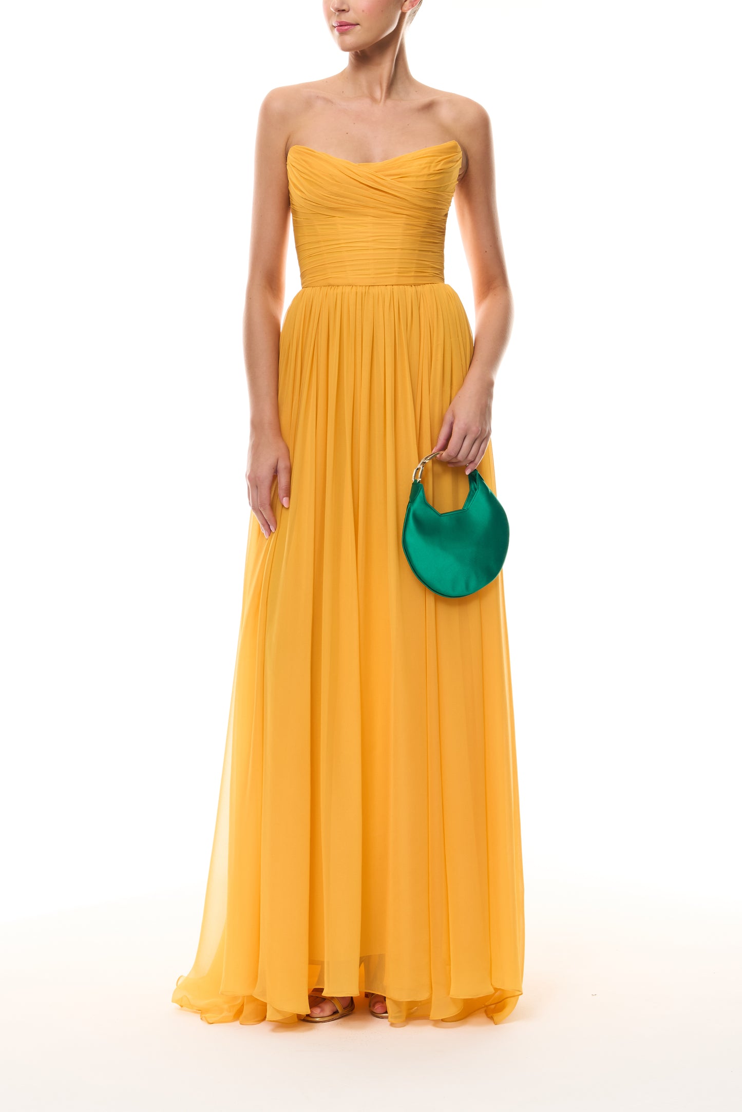 Monique Lhuillier Spring 2026 strapless Mango chiffon draped bodice gown - front with Emerald Demi evening bag.