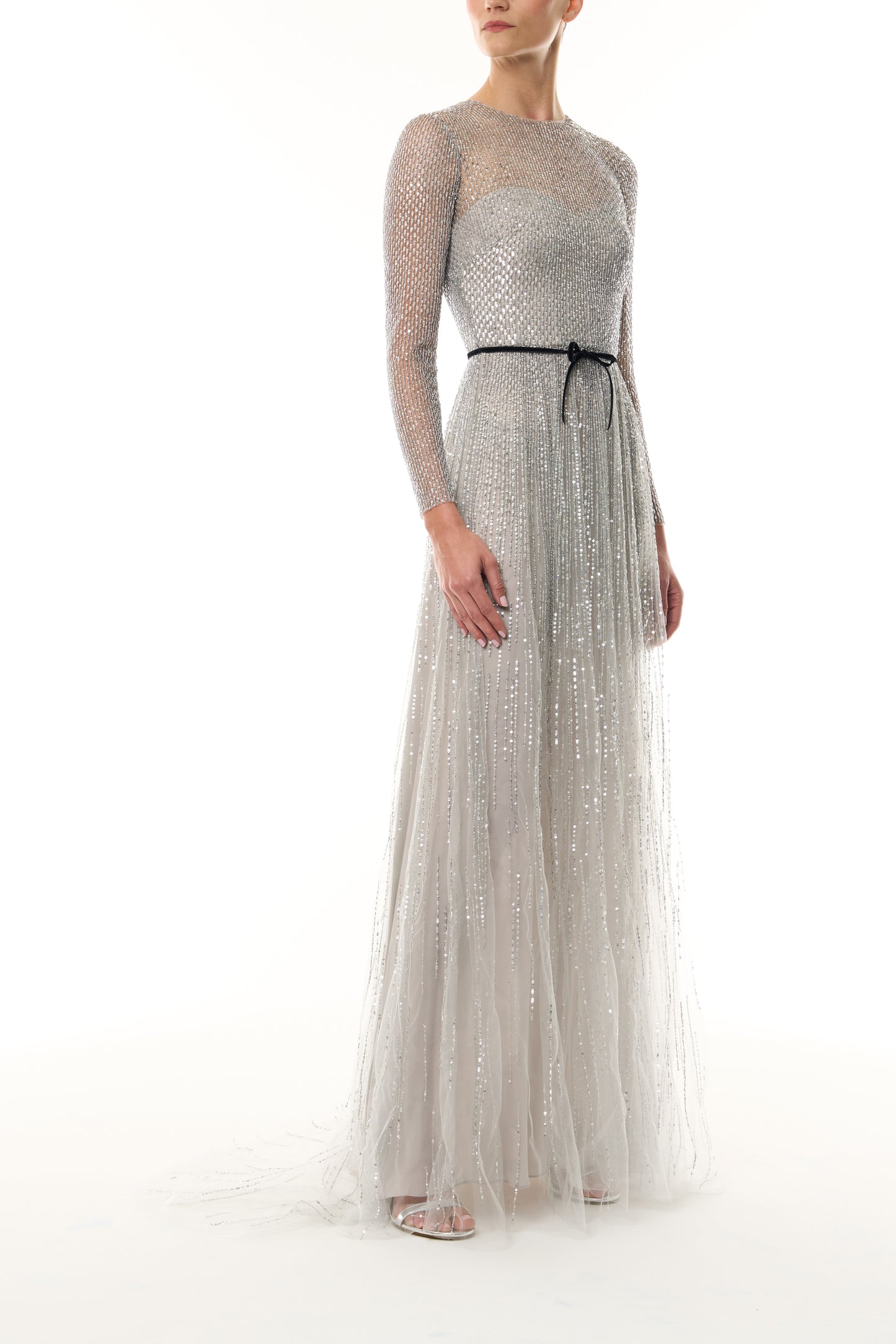 Monique Lhuillier Fall 2026 silver, long sleeve embroidered tulle gown with black velvet belt at waist - side.