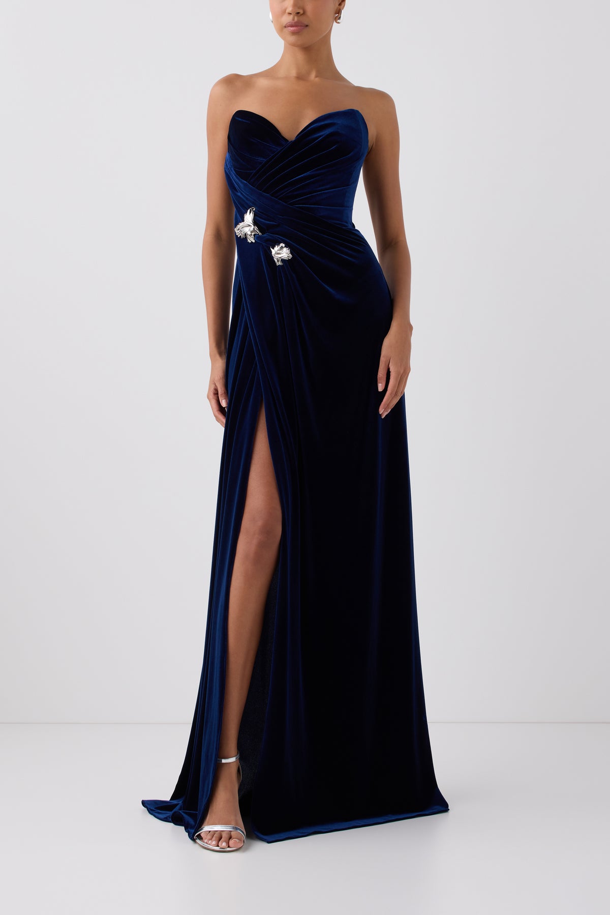 Monique Lhuillier Fall 2026 Navy stretch velour draped gown with slit and silver floral embellishment - front.