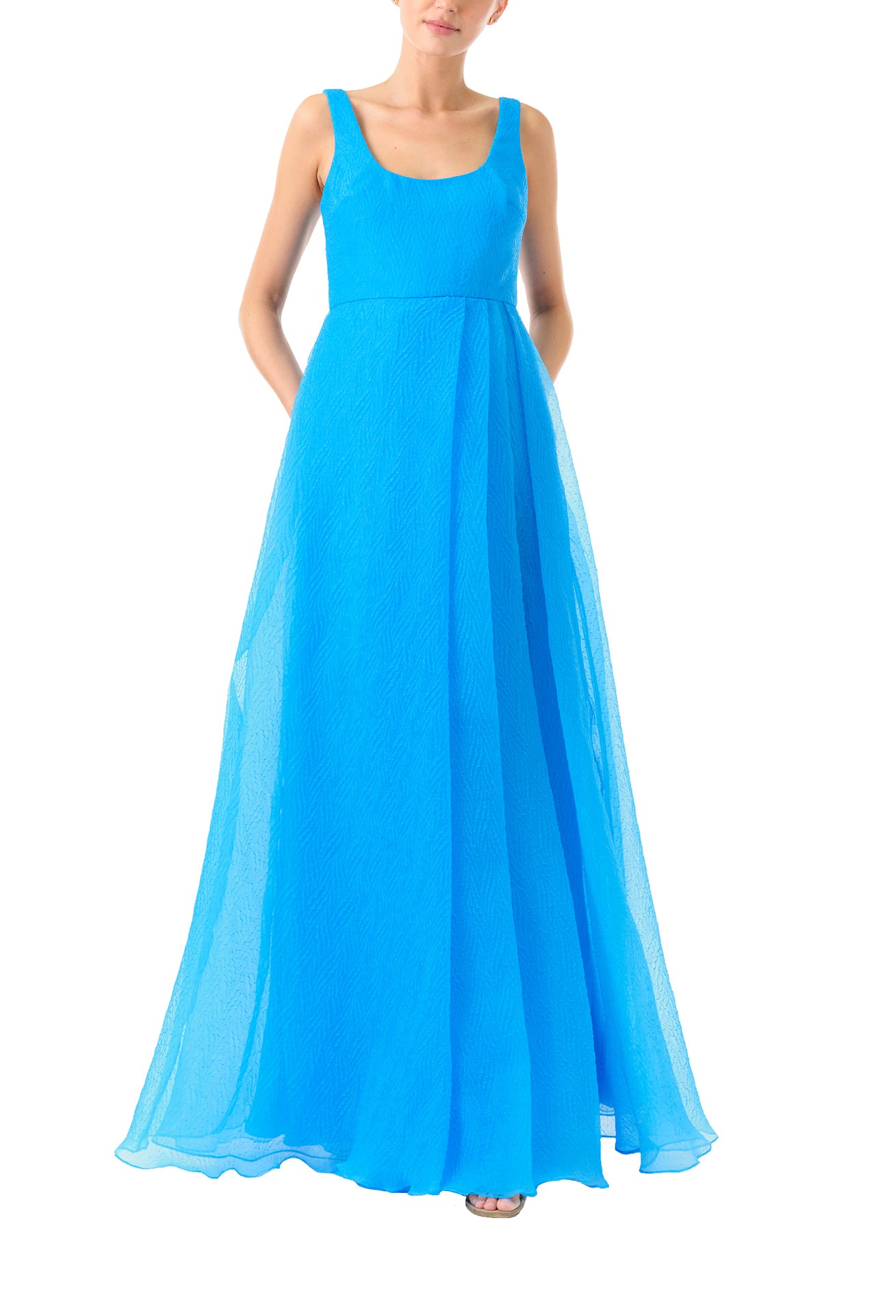 ML Monique Lhuillier 2024 scoop neck long dress with asymmetrical pleated front skirt and slit in Cyan Blue textured organza - front no slit.