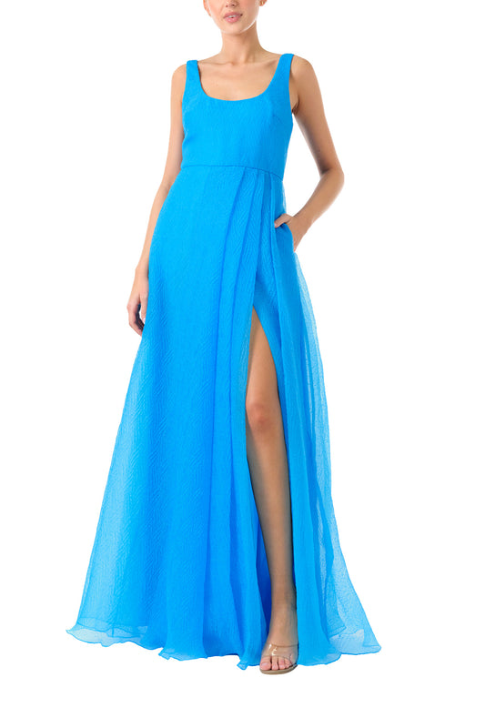 ML Monique Lhuillier 2024 scoop neck long dress with asymmetrical pleated front skirt and slit in Cyan Blue textured organza - front.