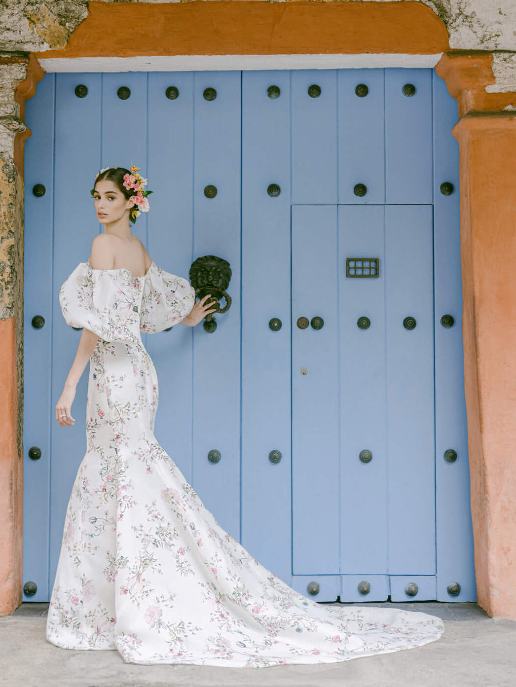 Woman wearing Monique Lhuillier Fall 2022 fitted ivory and floral print Amalia gown with billowed sleeve