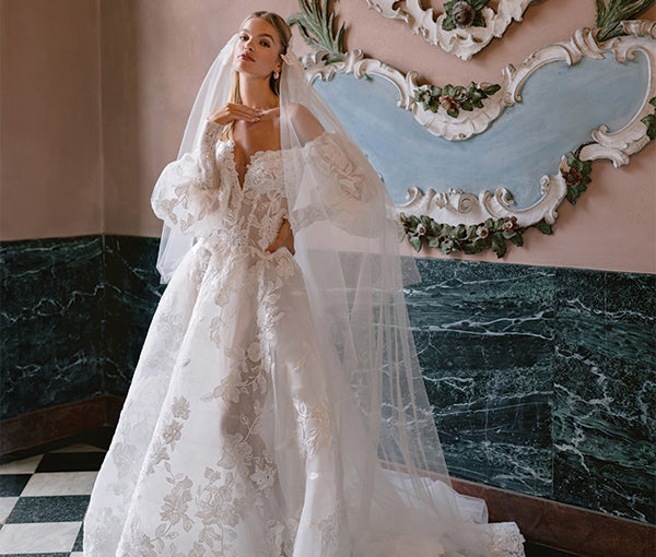 Monique Lhuillier Fall 2025 white Philippine ballgown with embroidered sequin lace and puff sleeves on model in front of marble wall
