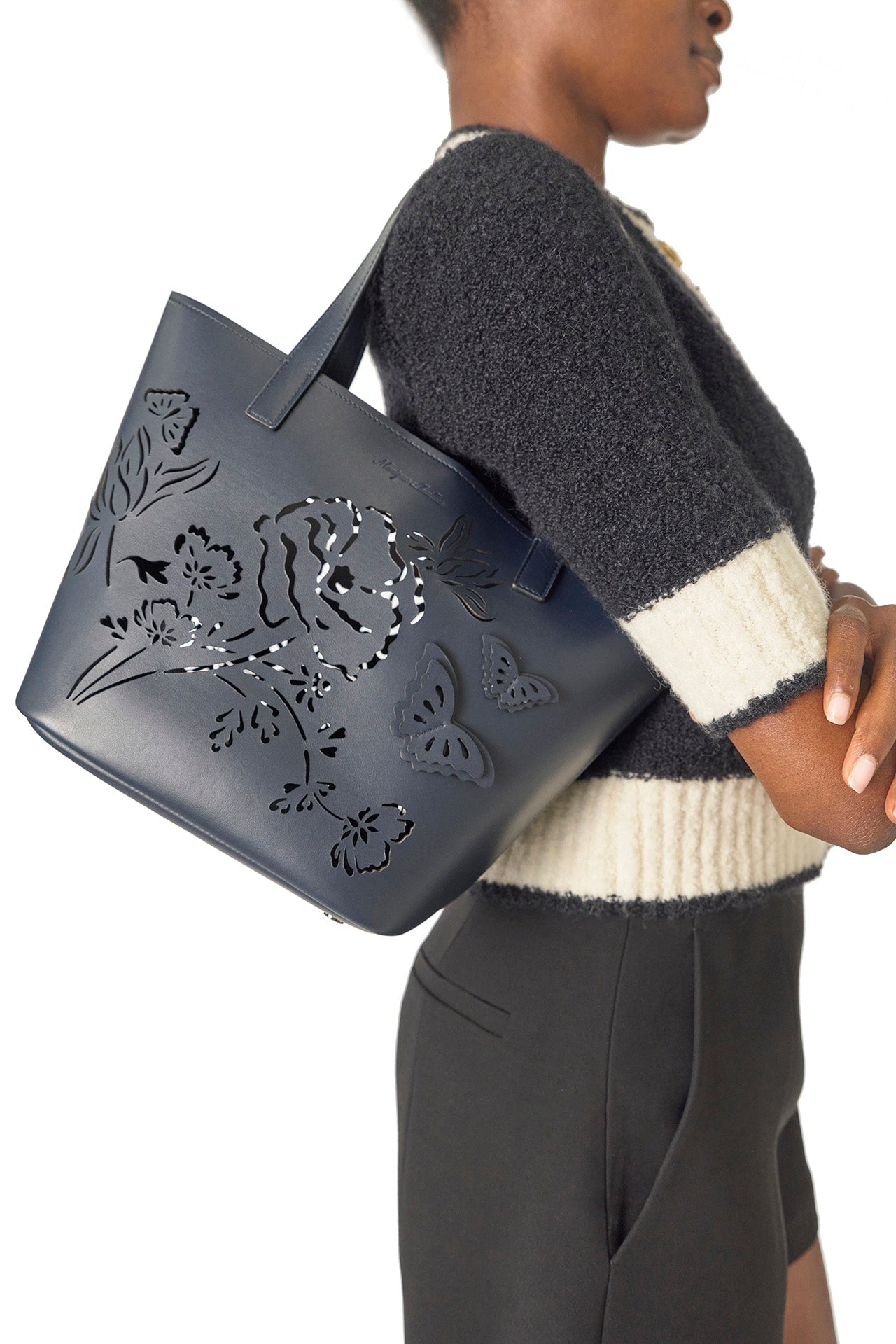 Monique Lhuillier Spring 2025 Short sleeve knit cardigan in Noir/Silk White Boucle - side with Colette tote in Navy.