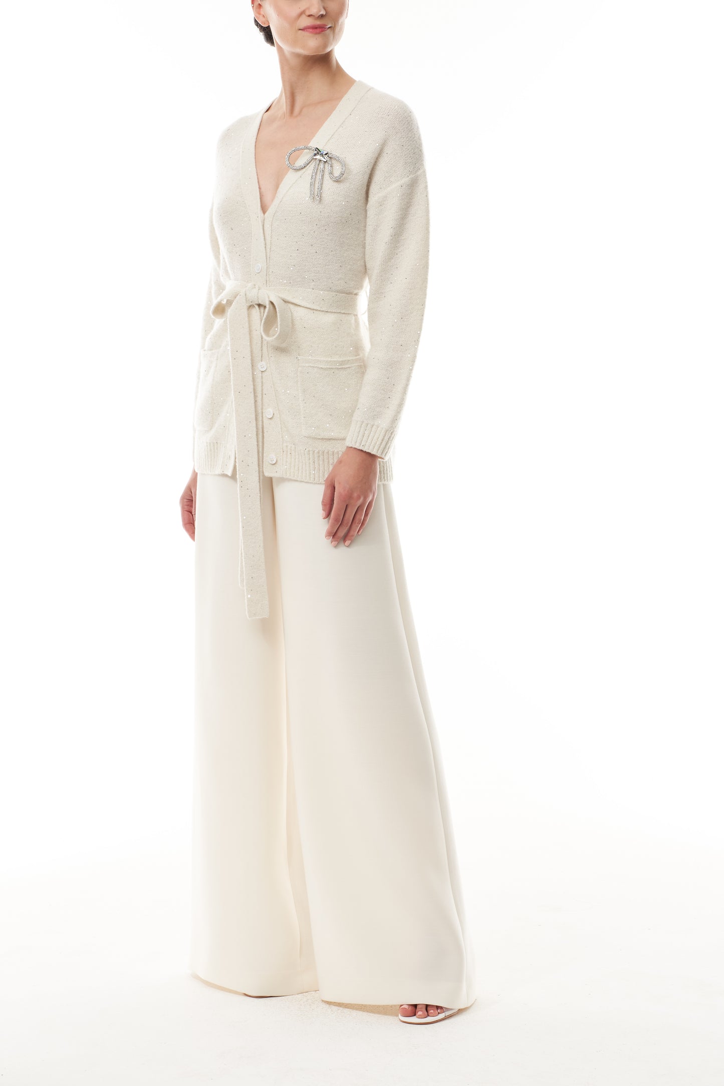 Monique Lhuillier Fall 2025 long sleeve cardigan in ivory sequin cashmere with bow brooch and self-tie belt - side.