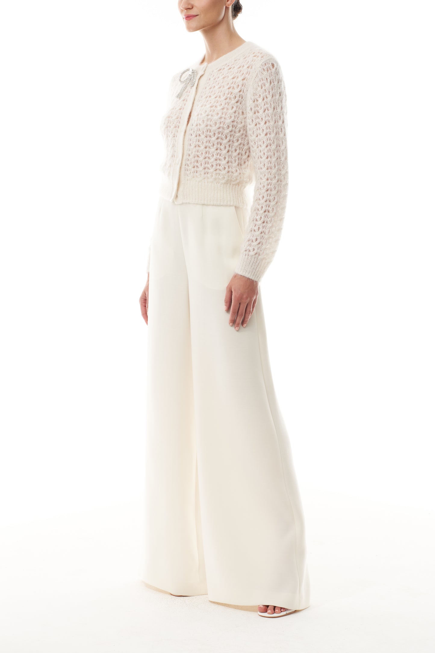 Monique Lhuillier Fall 2025 Mohair Silk Cashmere cardigan with brooch and white wide leg trouser- side.