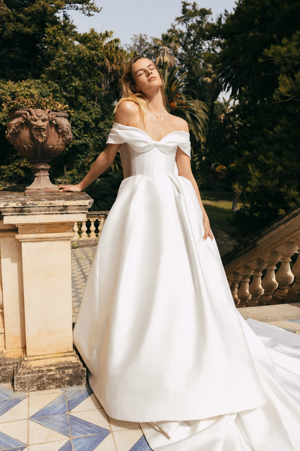 Woman wearing Monique Lhuillier Spring 2023 white mikado corseted off-the-shoulder Luisa ballgown