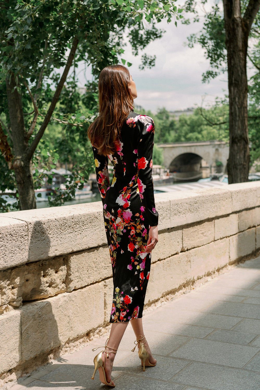Monique Lhuillier Spring 2024 long sleeve midi dress with high neck and tied front keyhole bodice in black floral hammered silk - back of model.