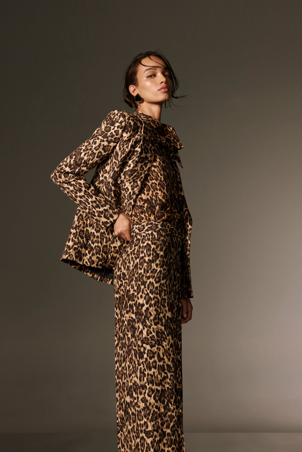 Monique Lhuillier Spring 2026 lookbook image - model wearing leopard georgette scarf neck blouse with leopard suiting straight leg trouser and tuxedo jacket