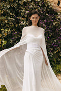 Woman wearing white sequin strapless Monique Lhuillier Spring 2023 Pearla draped column gown with white chiffon Pearla cape
