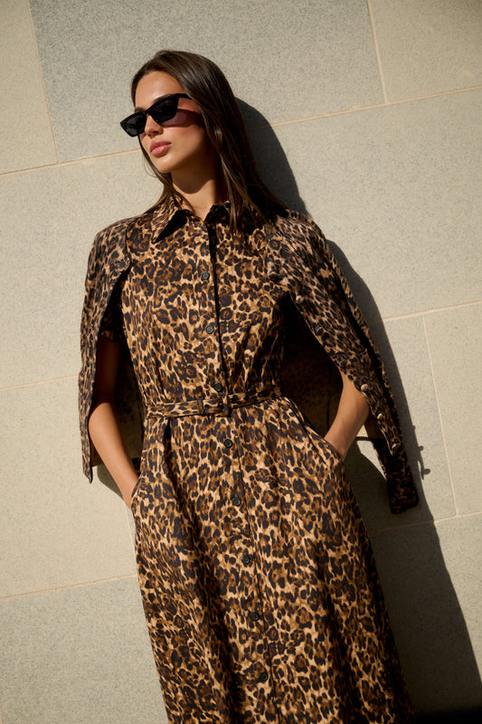 Monique Lhuillier Spring 2026 Leopard Printed Cotton Poplin short sleeve shirt
dress with belt and leopard cashmere cardigan - model leaning on wall outside.