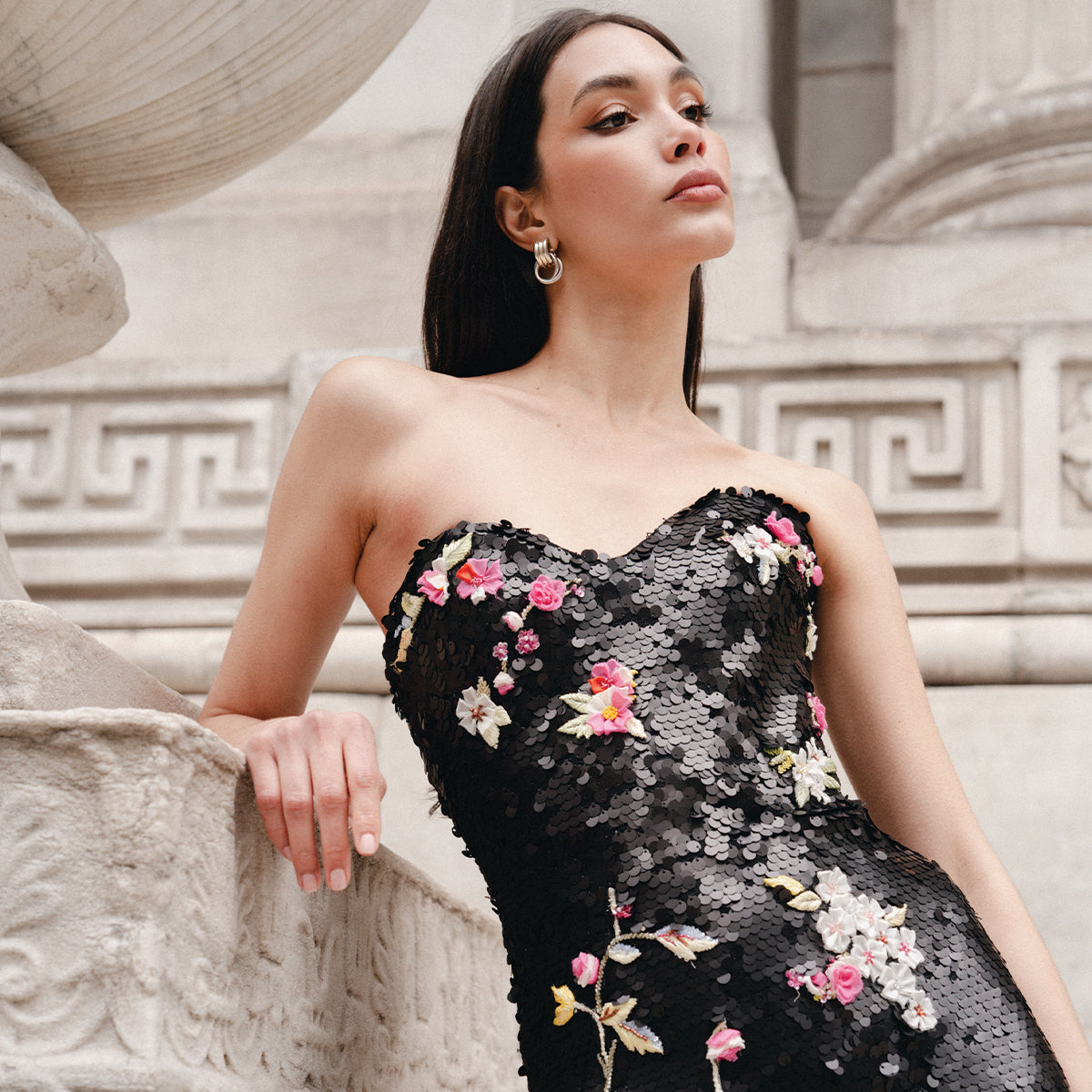 Monique Lhuillier Fall 2025 Noir Multi Floral Embroidered Matte Sequin Strapless Column gown - lookbook photo of model leaning on sculpture.