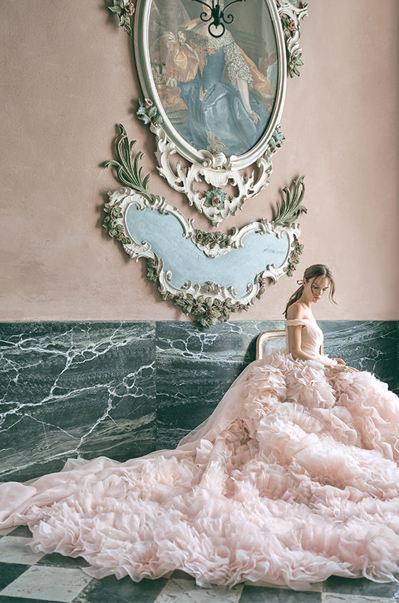 Woman wearing Monique Lhuillier Fall 2020 blush off-the-shoulder organza Secret Garden gown with rosette textured skirt and back streamers