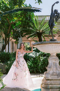 Woman wearing Monique Lhuillier Spring 2024 strapless sweetheart blush English Rose ballgown with blush and green 3-D floral applique