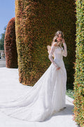Woman wearing Monique Lhuillier Spring 2024 white lace a-line Lawrence gown with long sleeve off-the-shoulder matching lace jacket