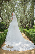 Woman in white lace Monique Lhuillier Spring 2021 Magnificent ballgown and lace long sleeve jacket and Magnificent veil with lace trim