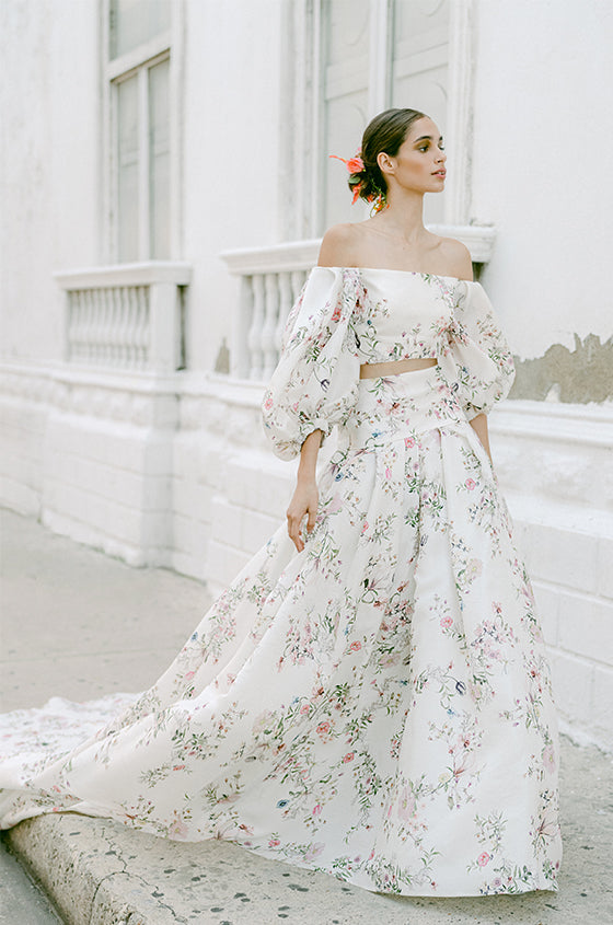 Woman wearing Monique Lhuillier Fall 2022 ivory and floral printed Alice bodice with billowed sleeve and matching Alice ball skirt
