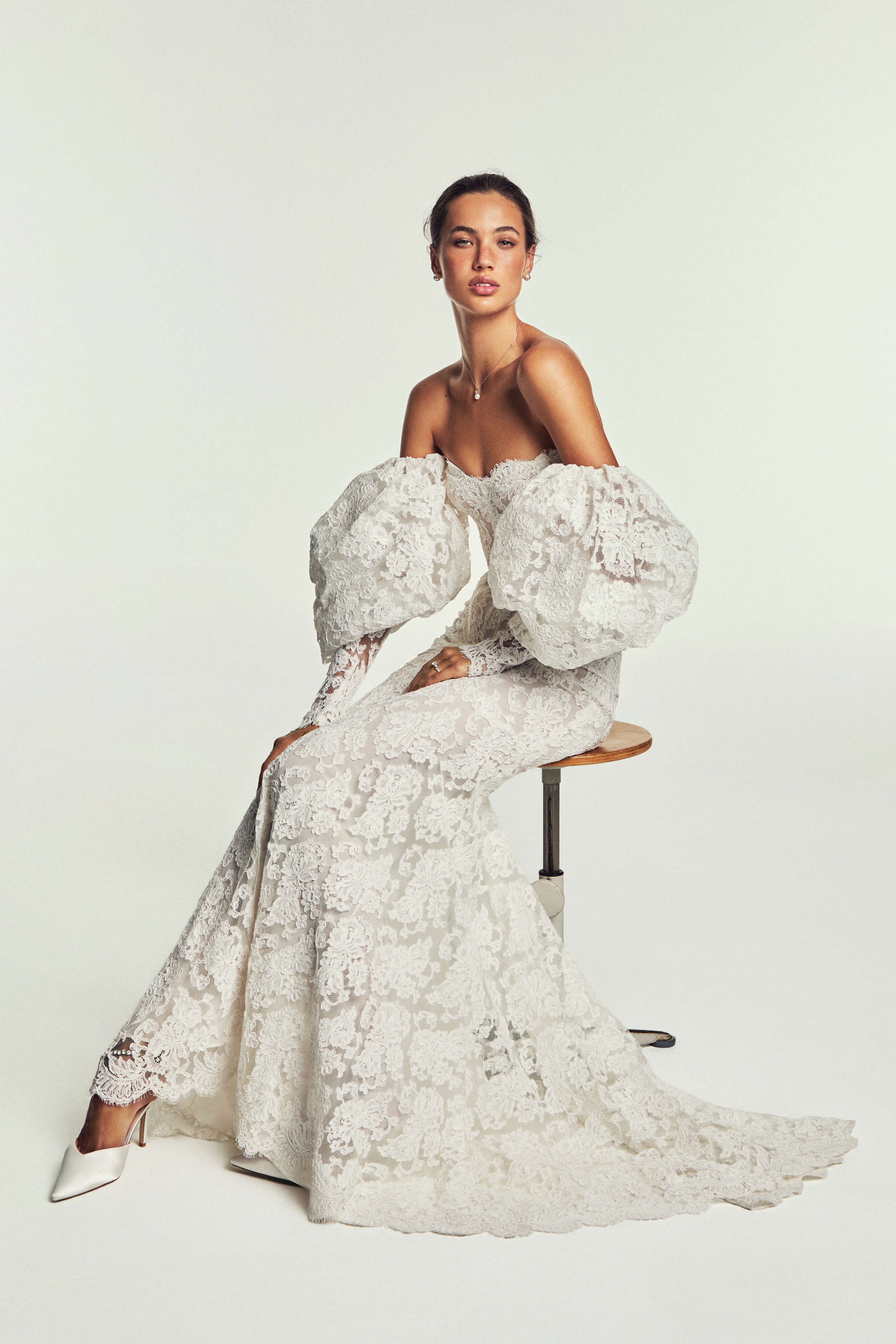 Monique Lhuillier Spring 2027 Bridal Two-piece Revel strapless corset bodice and trumpet skirt in ivory French re-embroidered lace with puff sleeves.