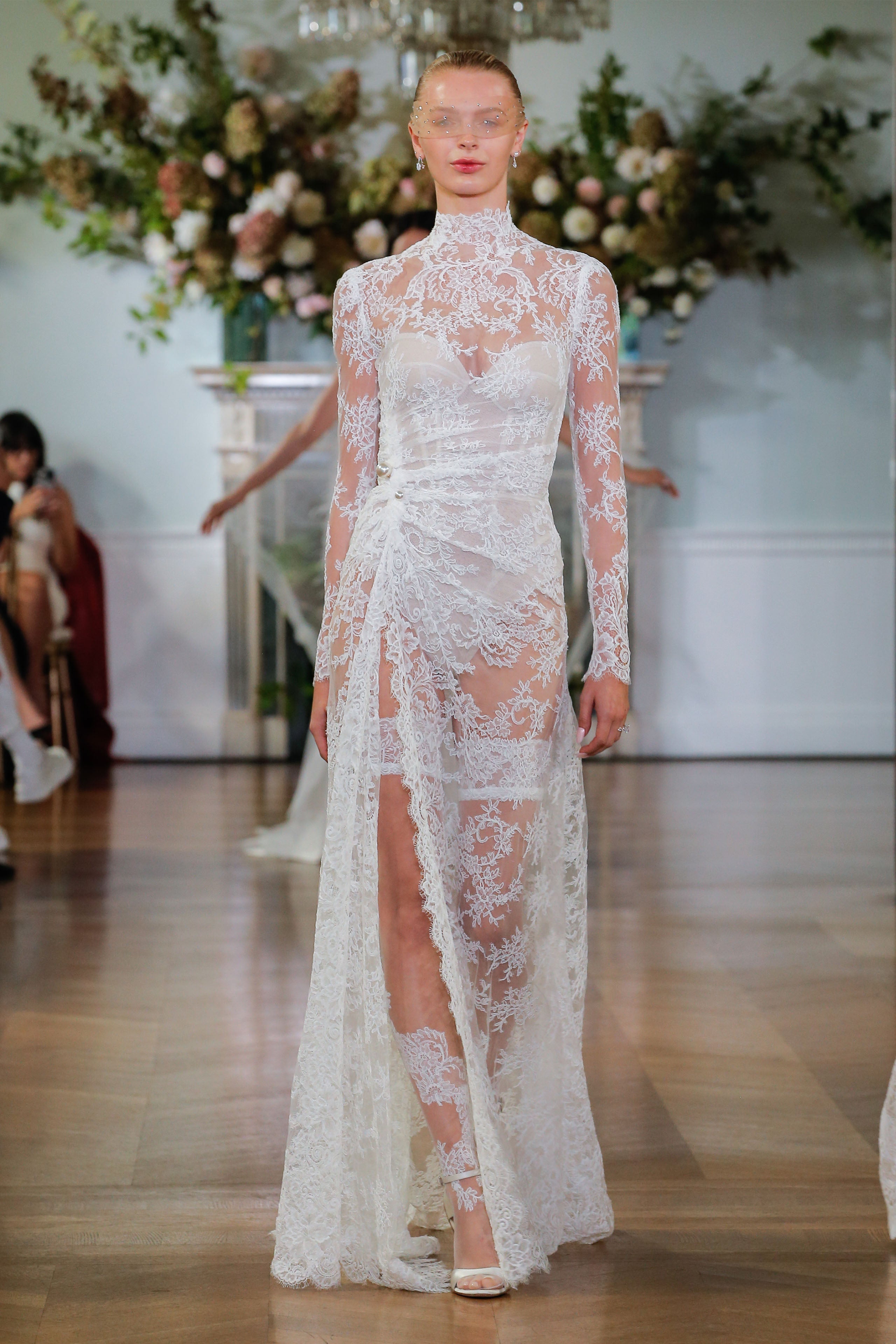 Monique Lhuillier Fall 2026 Bridal silk white re-embroidered lace high neck long sleeve draped Rowan sheath gown with slit - runway.