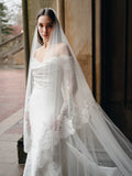 Mikado trumpet gown with draped bodice, lace sleeves and lace hem border.Paired with the Cathedral length, two tier lace trimmed veil.