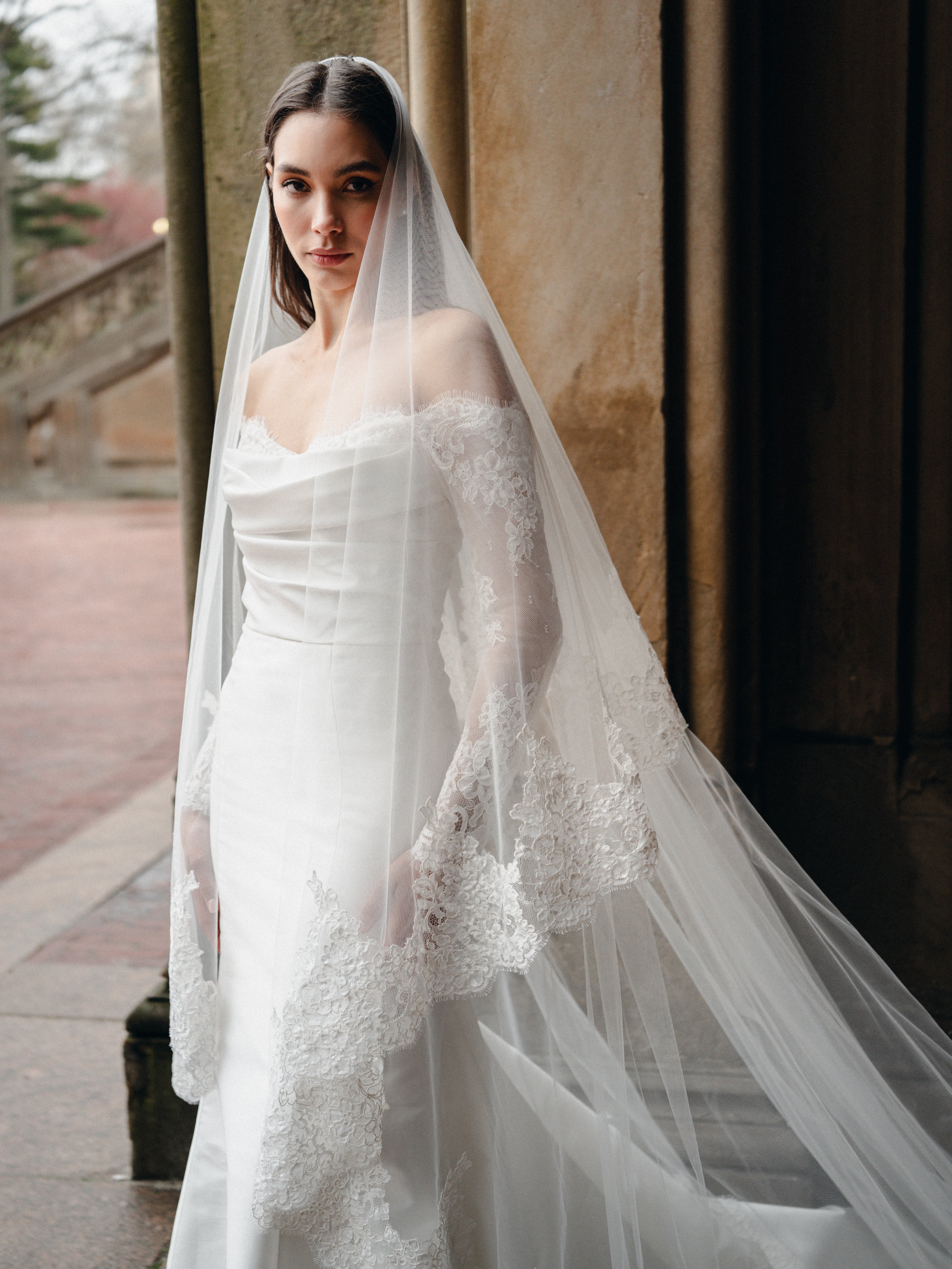 Mikado trumpet gown with draped bodice, lace sleeves and lace hem border.Paired with the Cathedral length, two tier lace trimmed veil.