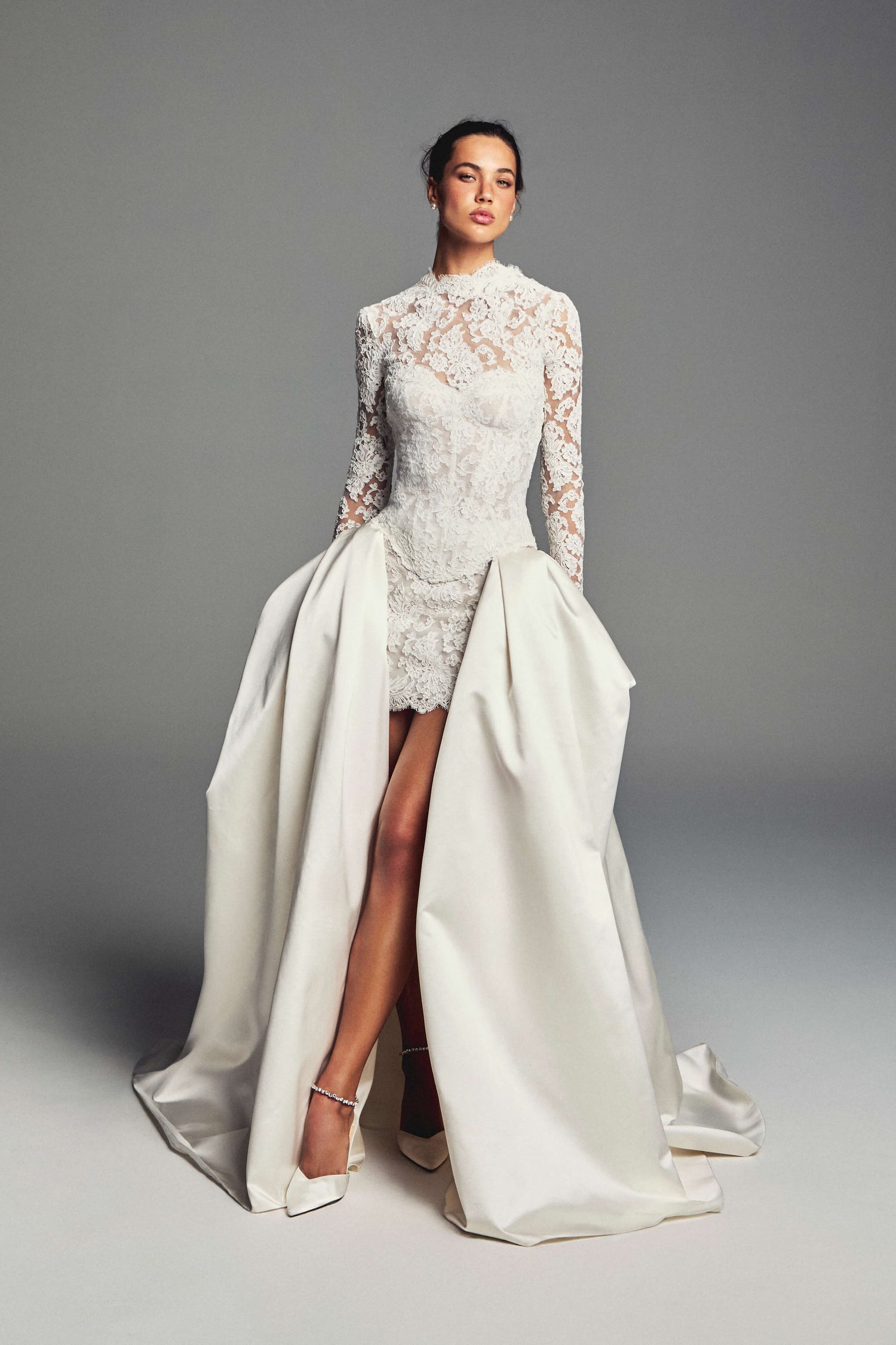 Monique Lhuillier Spring 2027 Bridal Two-piece Revel strapless corset bodice and mini skirt in ivory French re-embroidered lace with long sleeve jacket with open scoop back and structured ball skirt in ivory silk duchesse satin.