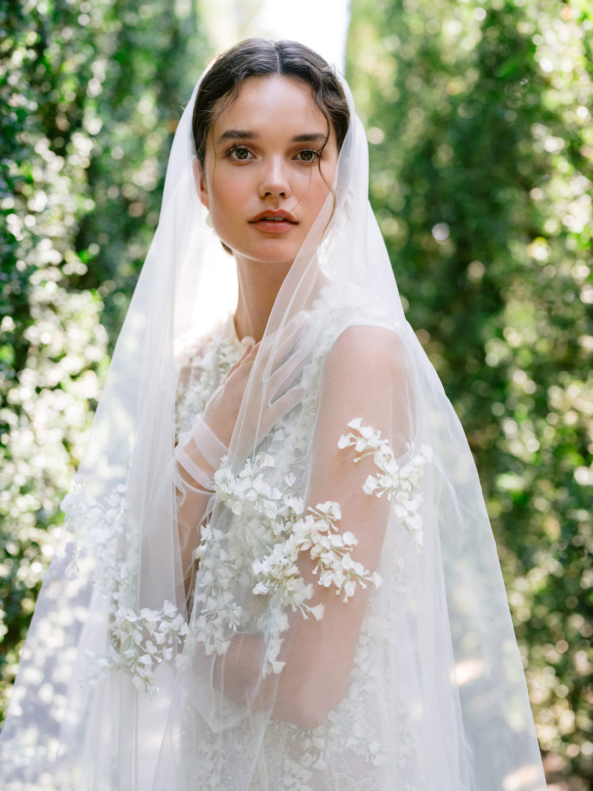 L'image montre une mariée portant une robe de mariée blanche sans manches avec des détails en dentelle complexes.