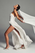 Monique Lhuillier Spring 2027 Bridal Strapless hand draped drop waist Mercer sheath gown with high leg slit in silk white chiffon with cascading butterfly cut veil.