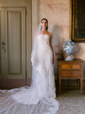 Woman wearing Monique Lhuillier Fall 2024 white lace fitted Lucky gown with matching tulle and lace veil