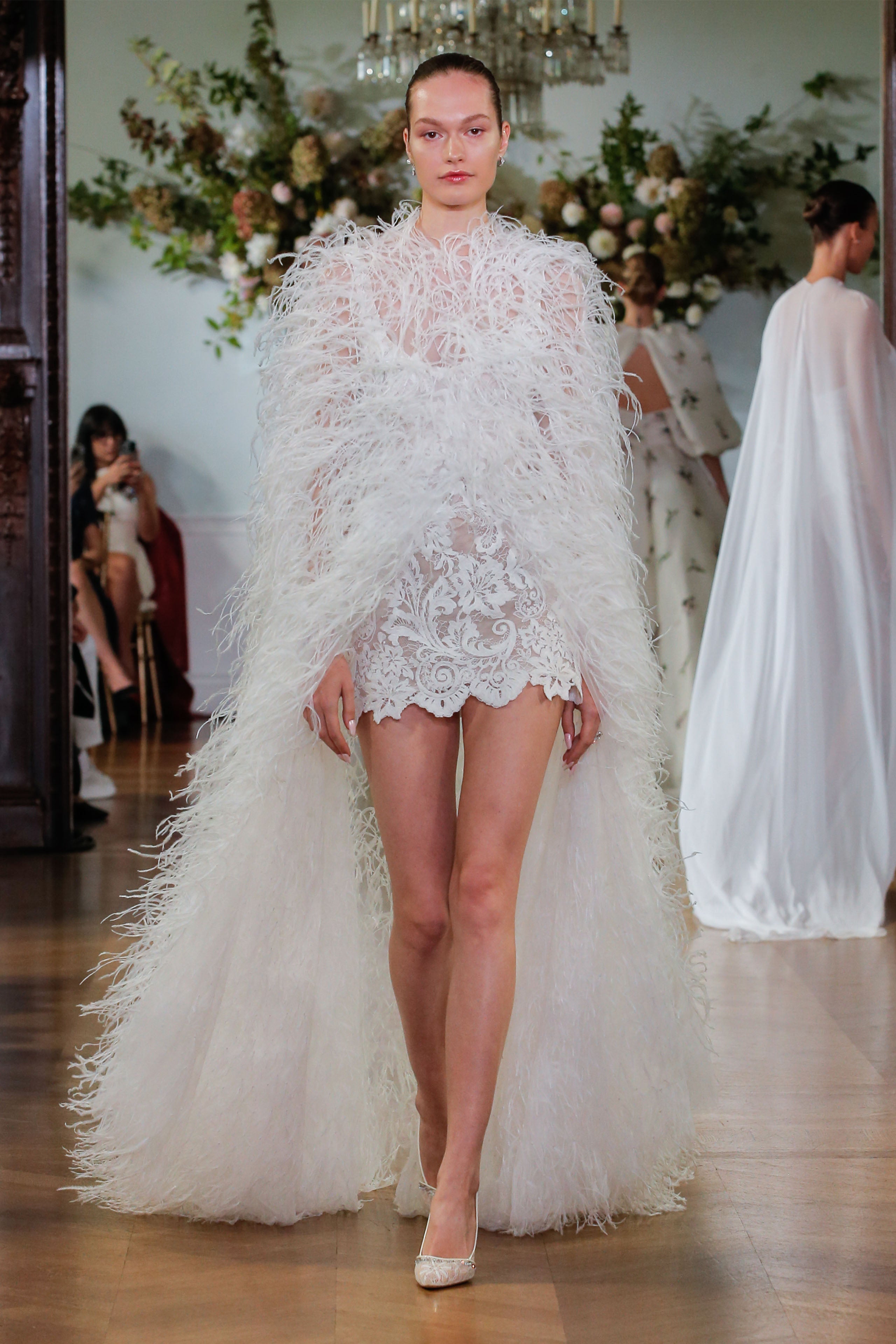 Monique Lhuillier Fall 2026 Bridal silk white/pearl scoop neck lace Rhiannon mini dress with feather floor length cape- runway.