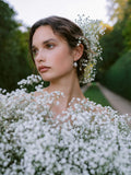 Close up of woman holding a bouquet of baby's breath with baby's breath in her hair