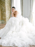 Woman sitting in white strapless Monique Lhuillier Fall 2021 Daydream ballgown with organza layered ruffle skirt