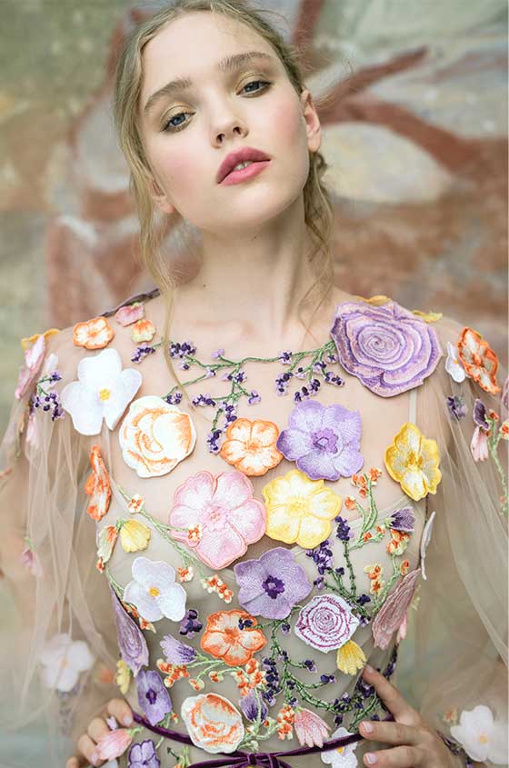 Woman wearing Monique Lhuillier Spring 2022 multicolored floral embroidered sheer billowed sleeve a-line gown style 22134