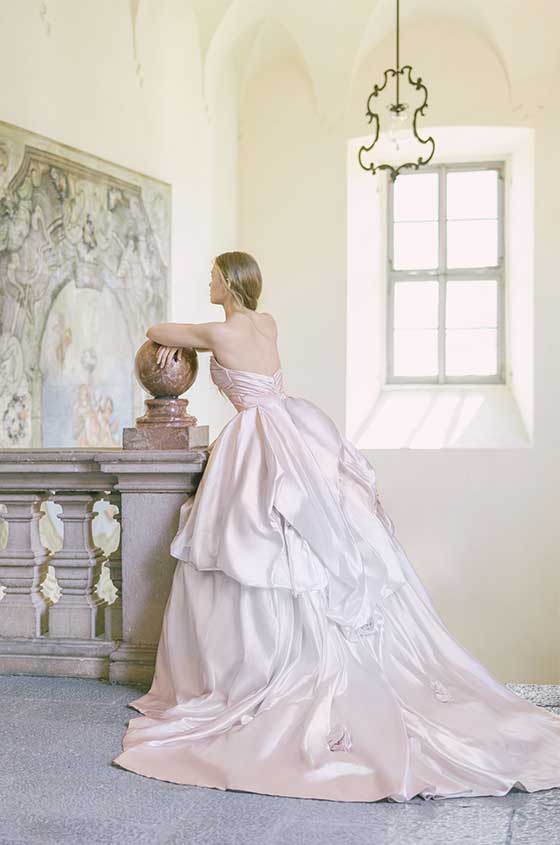 Woman wearing Monique Lhuillier Spring 2022 blush ombre satin Rose ballgown with tufted skirt and rosette accents