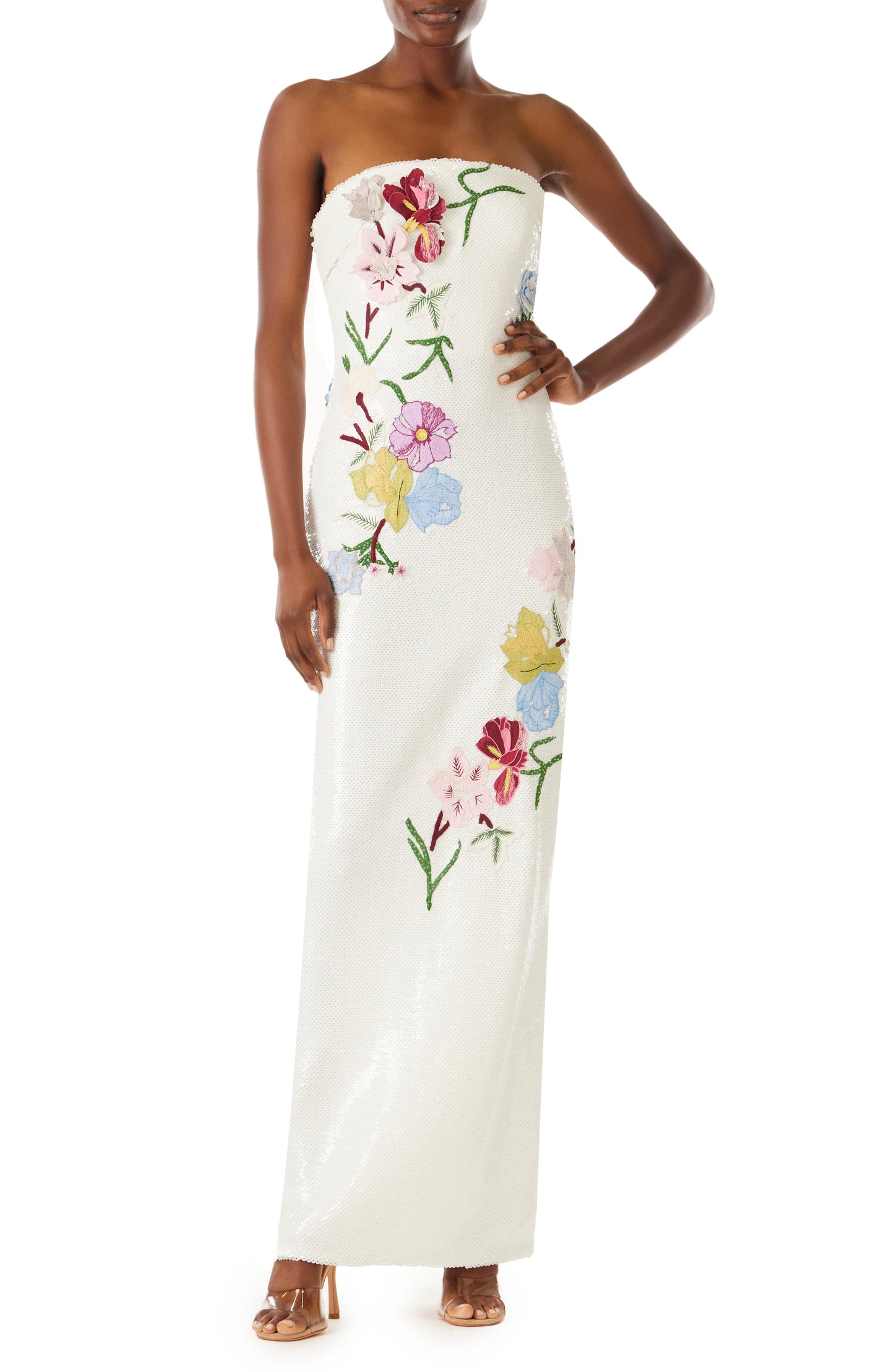 Black model in white sequin floor length gown with multi colored floral embroidery.