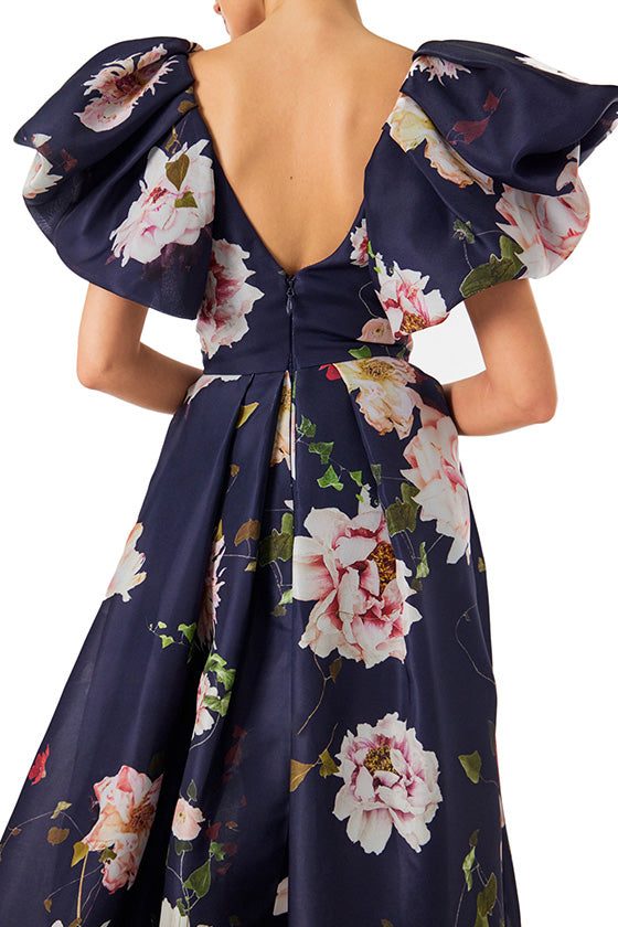 Monique Lhuillier navy floral gazar gown with deep v neckline, ruffle flutter sleeves and pockets.