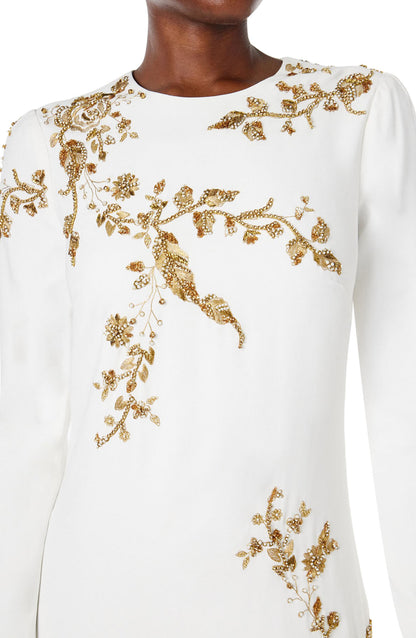 Monique Lhuillier silk white jewel neck, long sleeve column gown with gold embroidery.