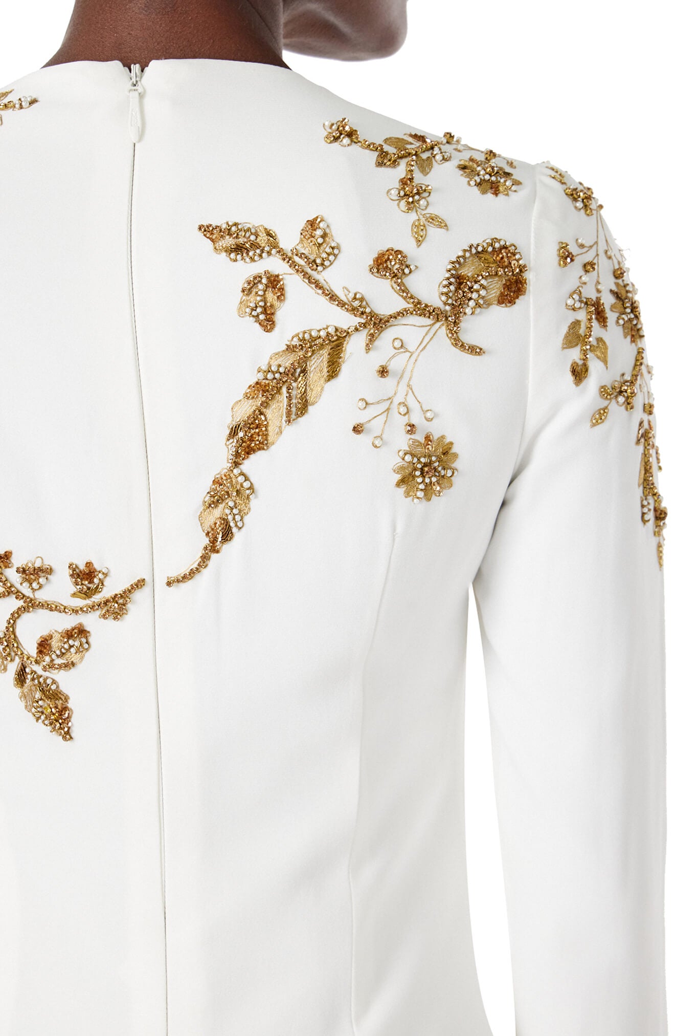 Monique Lhuillier silk white jewel neck, long sleeve column gown with gold embroidery.