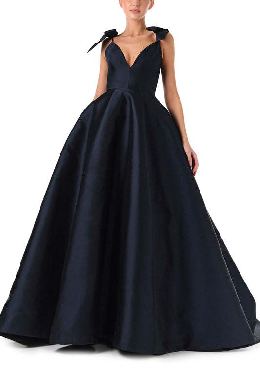 Monique Lhuillier Fall 2024 deep V-neck ball gown in navy mikado with full skirt and bow detail at shoulders - front.