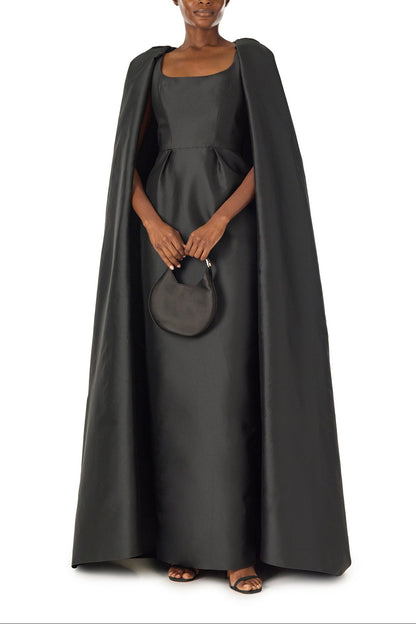 Monique Lhuillier Fall 2024 sleeveless, scoop neck column gown with integral cape in noir mikado fabric - front with Demi bag.
