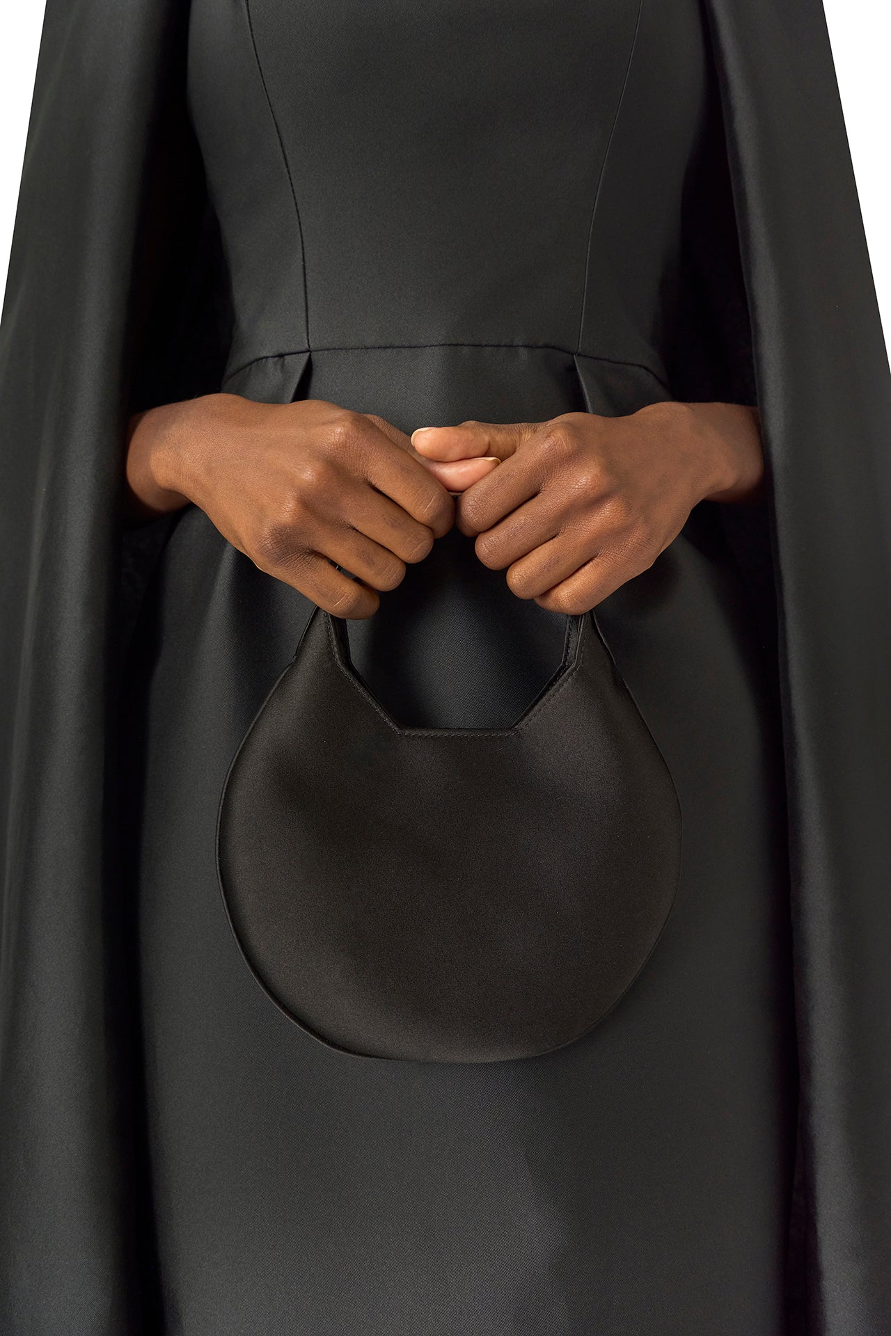 Monique Lhuillier Fall 2024 sleeveless, scoop neck column gown with integral cape in noir mikado fabric - Demi bag.